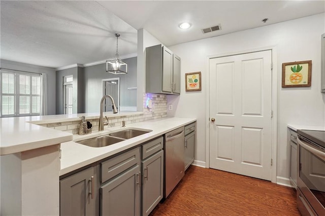 kitchen with a sink, light countertops, appliances with stainless steel finishes, gray cabinets, and decorative light fixtures