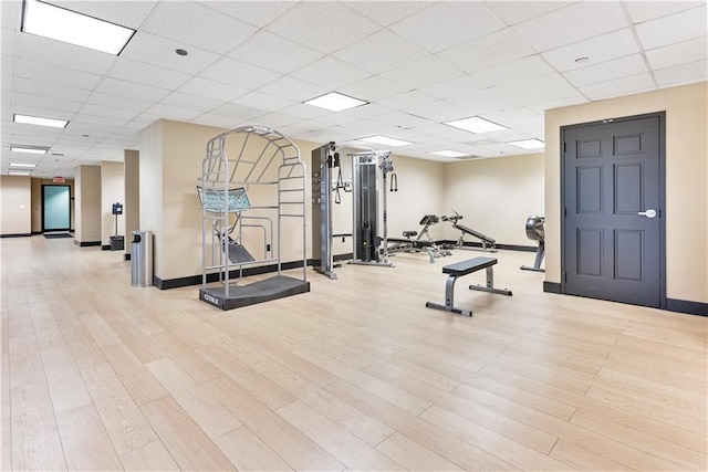 exercise room with a drop ceiling and light hardwood / wood-style flooring