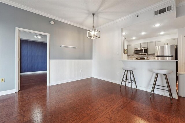 spare room featuring a notable chandelier, dark wood-type flooring, and crown molding