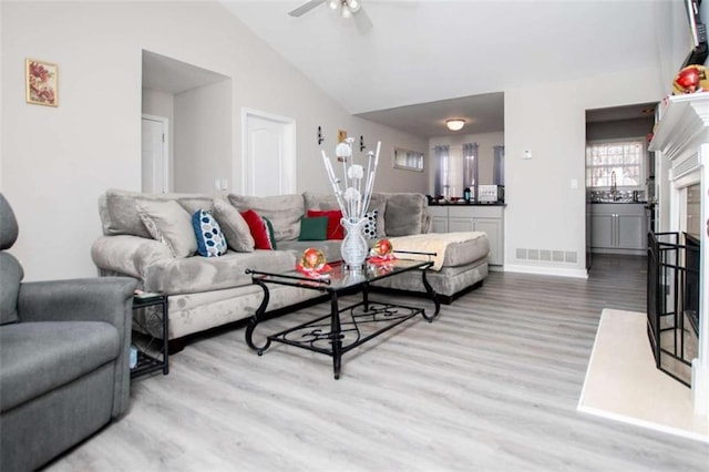 living room with high vaulted ceiling, wood finished floors, visible vents, baseboards, and a ceiling fan