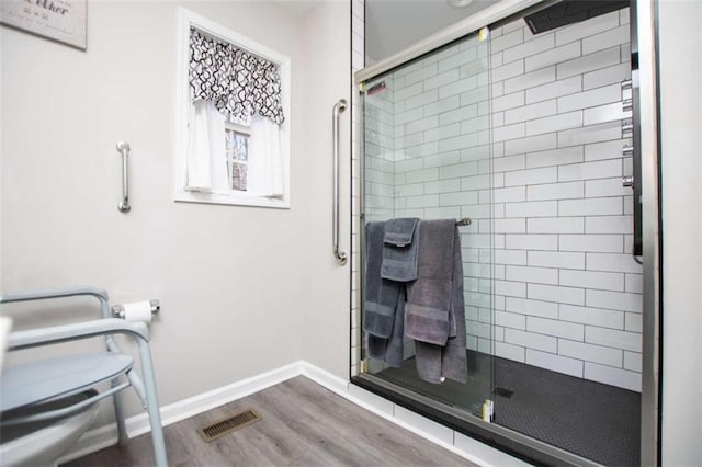 full bath with visible vents, toilet, a stall shower, wood finished floors, and baseboards