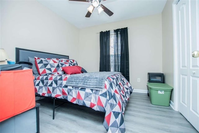 bedroom featuring ceiling fan, baseboards, and wood finished floors