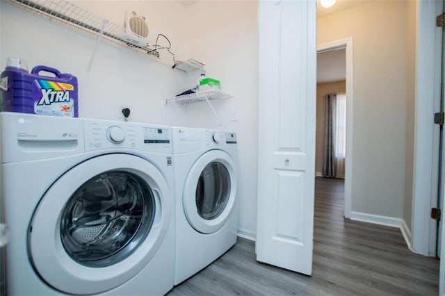 laundry room with washing machine and dryer, laundry area, baseboards, and wood finished floors