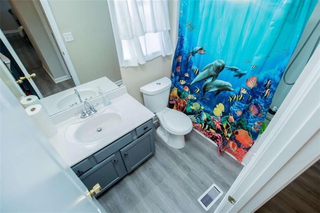 bathroom featuring toilet, a shower with shower curtain, wood finished floors, vanity, and visible vents