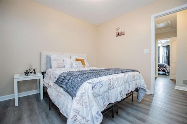 bedroom with visible vents, wood finished floors, attic access, and baseboards