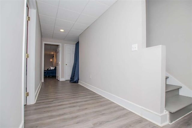 corridor featuring a paneled ceiling, recessed lighting, stairway, wood finished floors, and baseboards