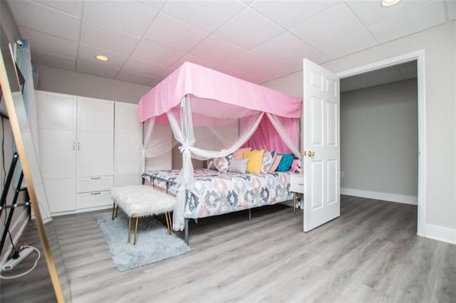 bedroom featuring a paneled ceiling, baseboards, wood finished floors, and recessed lighting