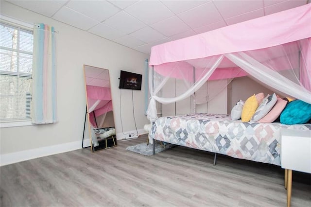 bedroom featuring a paneled ceiling, baseboards, and wood finished floors