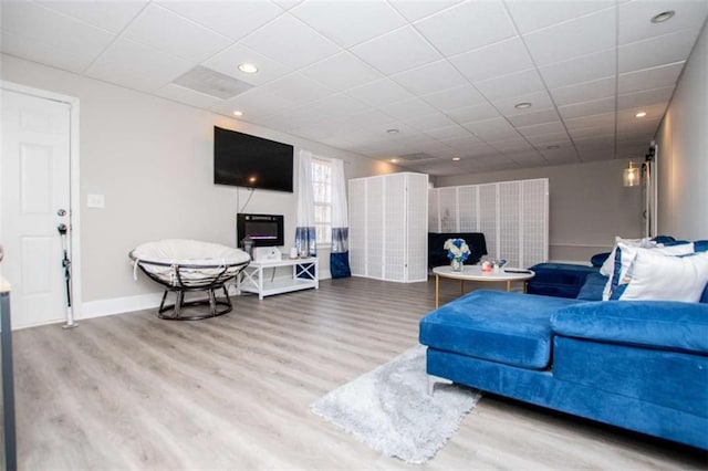 living area with recessed lighting, wood finished floors, a paneled ceiling, and baseboards