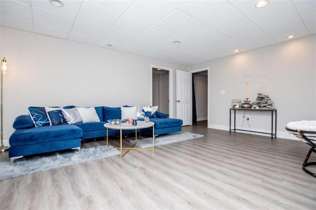 living area featuring a drop ceiling, recessed lighting, wood finished floors, and baseboards