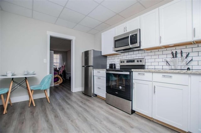 kitchen with a paneled ceiling, tasteful backsplash, appliances with stainless steel finishes, and white cabinets