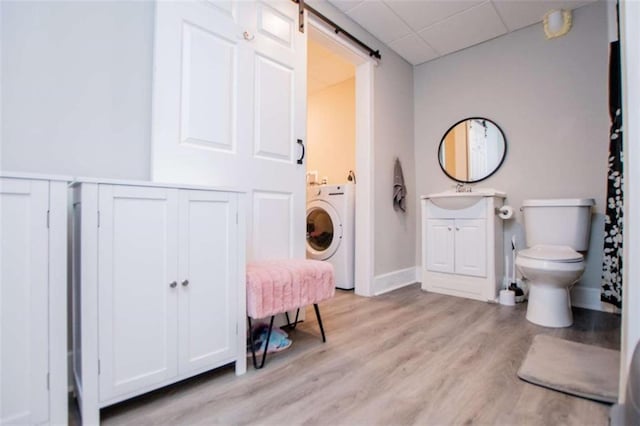 bathroom featuring toilet, a paneled ceiling, wood finished floors, vanity, and washer / clothes dryer