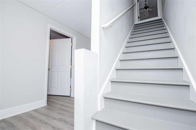 stairs featuring a drop ceiling, wood finished floors, and baseboards