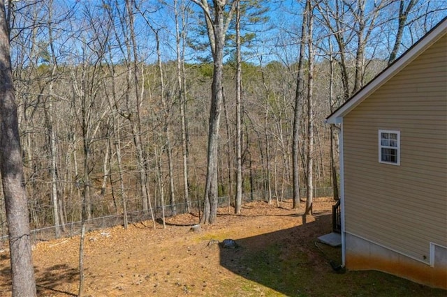 view of yard featuring a forest view and fence