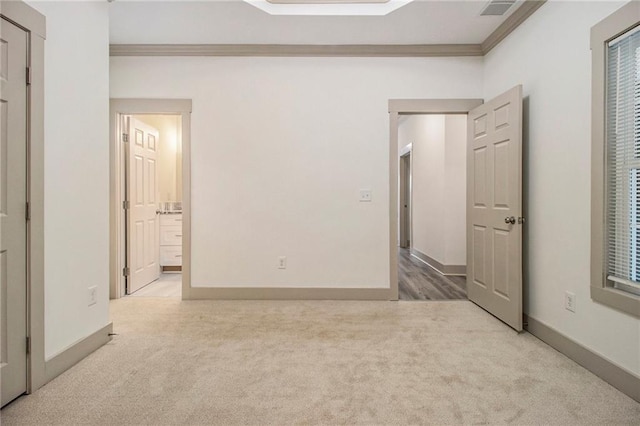 unfurnished bedroom featuring connected bathroom, light colored carpet, visible vents, baseboards, and crown molding