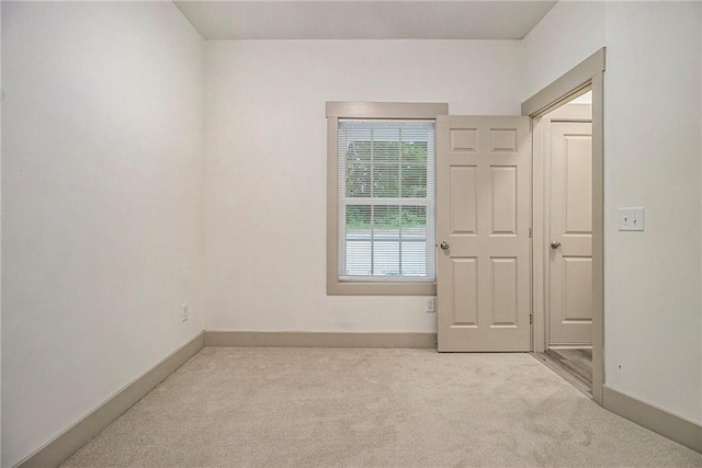 empty room featuring light carpet and baseboards