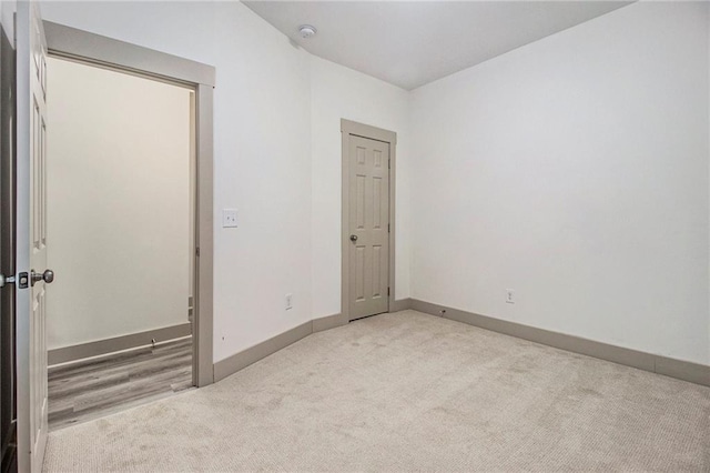 unfurnished room with light colored carpet and baseboards