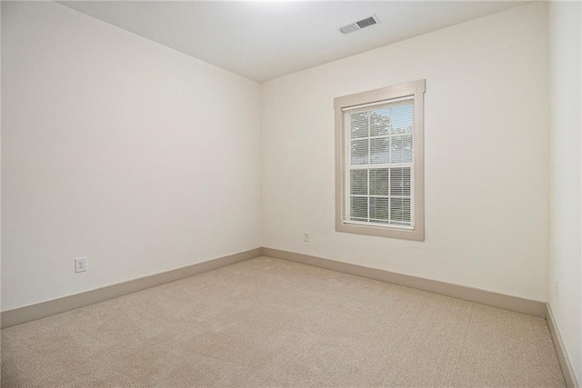 unfurnished room featuring baseboards, visible vents, and light colored carpet