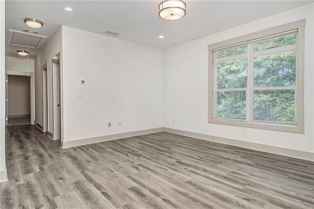 empty room with recessed lighting, visible vents, baseboards, light wood finished floors, and attic access