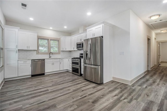 kitchen featuring stainless steel appliances, visible vents, decorative backsplash, white cabinets, and a sink