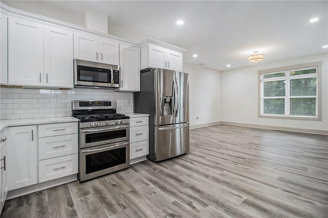 kitchen with tasteful backsplash, white cabinetry, stainless steel appliances, and light countertops