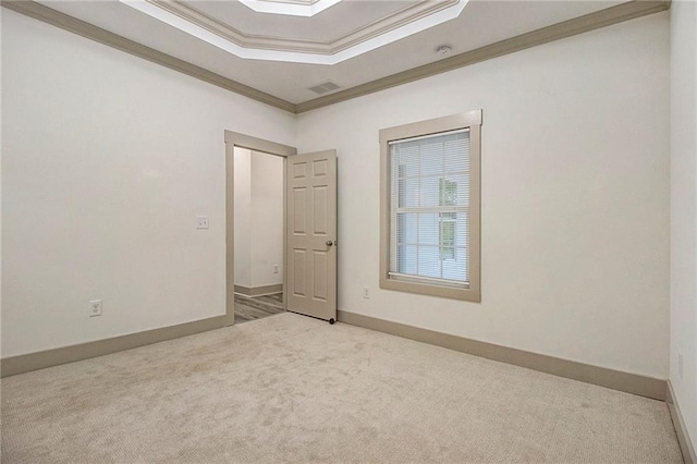 spare room with carpet flooring, visible vents, baseboards, ornamental molding, and a raised ceiling