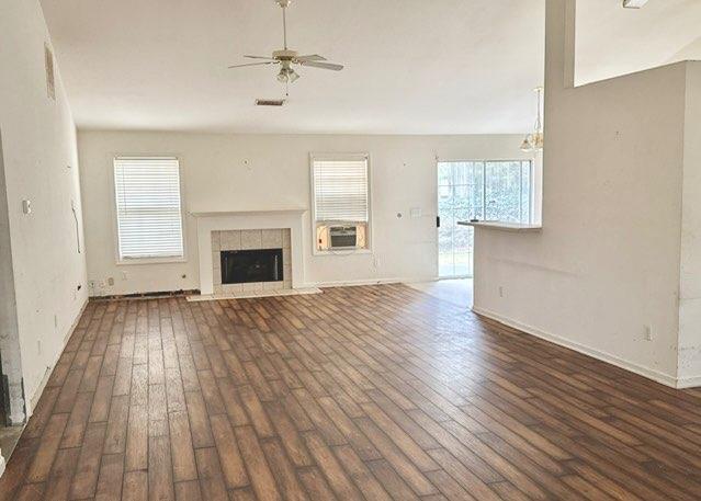 unfurnished living room featuring a tile fireplace, dark hardwood / wood-style floors, ceiling fan, and cooling unit