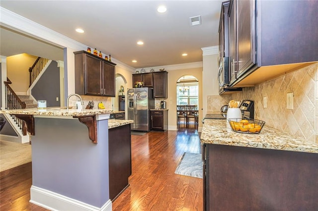 139 Village Park Dr, Newnan, GA 30265 - kitchen with stainless steel appliances, arched walkways, a peninsula, crown molding, and dark brown cabinetry