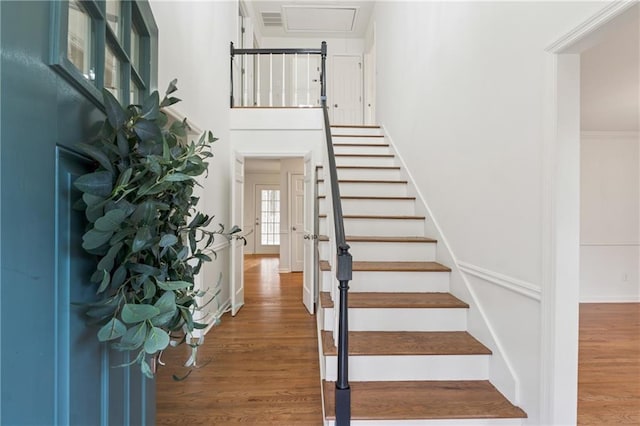 stairs with wood finished floors and a towering ceiling