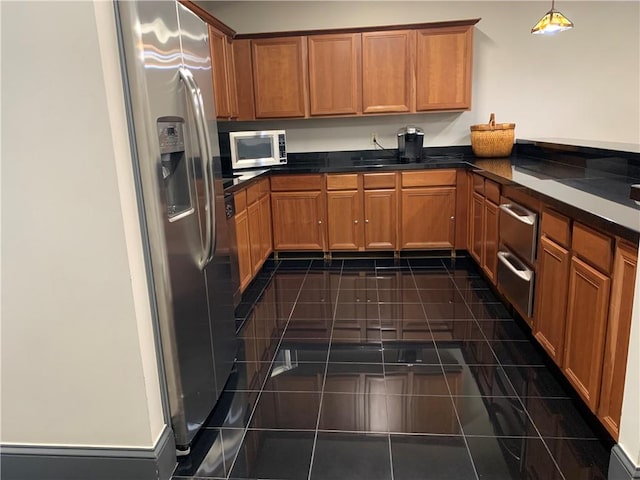 kitchen with appliances with stainless steel finishes, dark tile patterned floors, and pendant lighting