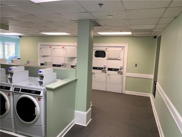 community laundry room featuring baseboards, washing machine and dryer, and stacked washer / drying machine