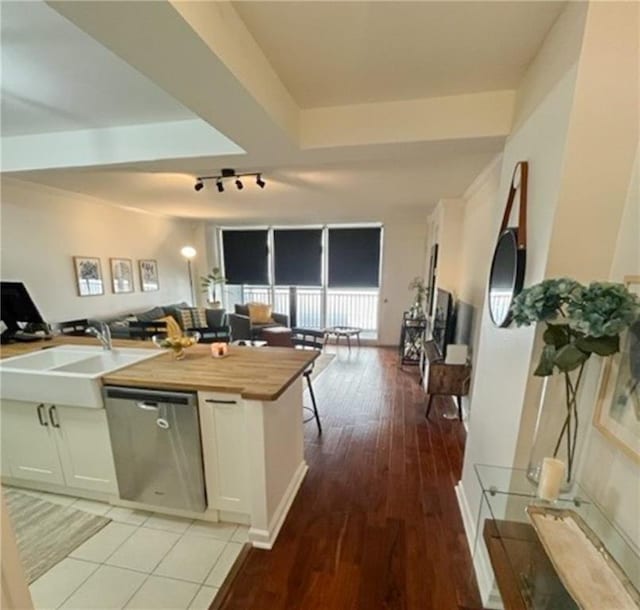 kitchen featuring light wood finished floors, open floor plan, white cabinetry, a sink, and dishwasher