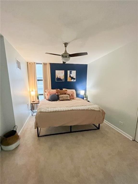 bedroom featuring baseboards, ceiling fan, visible vents, and light colored carpet