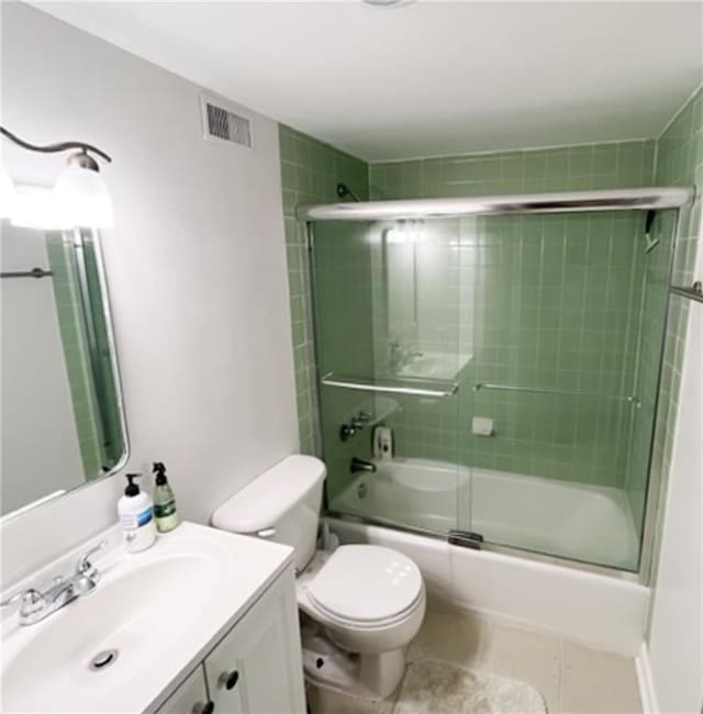 full bathroom with toilet, bath / shower combo with glass door, vanity, visible vents, and tile patterned floors