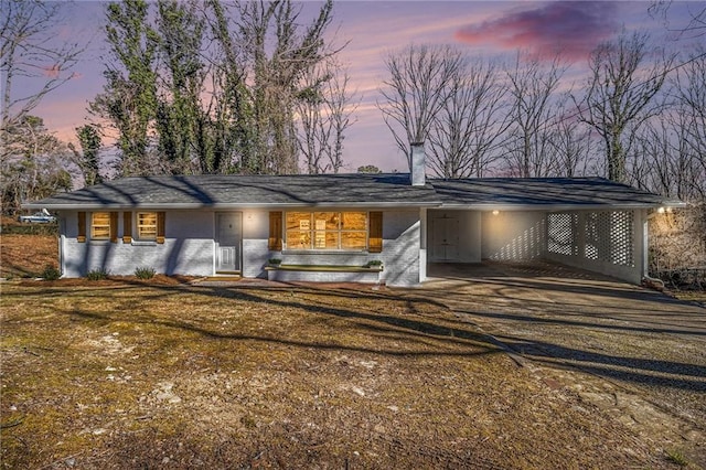 mid-century home with driveway, an attached carport, and brick siding