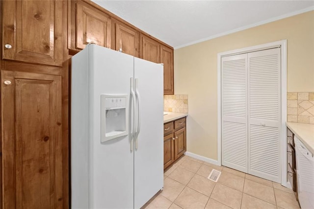 786 Mitsy Pt, Marietta, GA 30068 - kitchen featuring white fridge with ice dispenser, brown cabinetry, decorative backsplash, light countertops, and ornamental molding