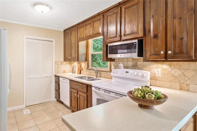 786 Mitsy Pt, Marietta, GA 30068 - kitchen with white appliances, crown molding, light countertops, brown cabinets, and tasteful backsplash