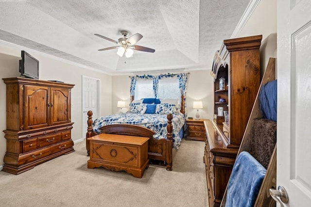 carpeted bedroom with a tray ceiling, ceiling fan, a textured ceiling, and ornamental molding