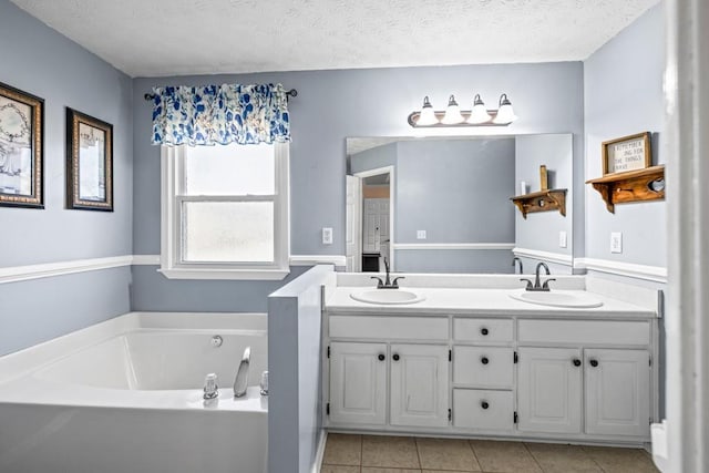 bathroom with a bathing tub, vanity, a textured ceiling, and tile patterned floors