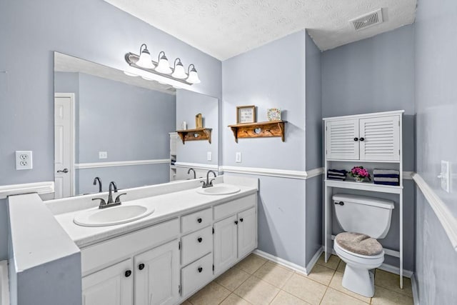 bathroom featuring tile patterned floors, vanity, a textured ceiling, and toilet