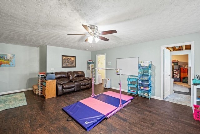 workout room featuring ceiling fan, dark hardwood / wood-style floors, and a textured ceiling