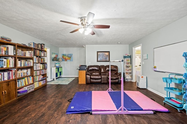 exercise area featuring ceiling fan, a textured ceiling, and dark wood-type flooring