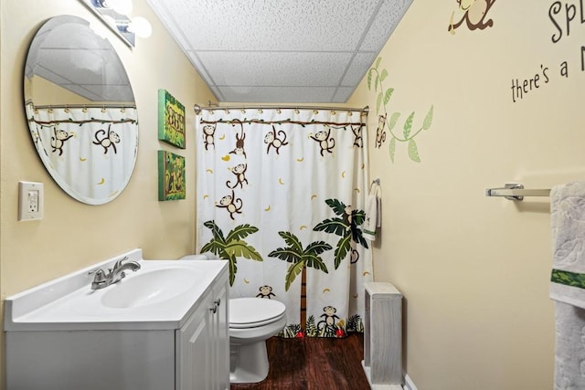 bathroom with a shower with shower curtain, a drop ceiling, vanity, hardwood / wood-style floors, and toilet