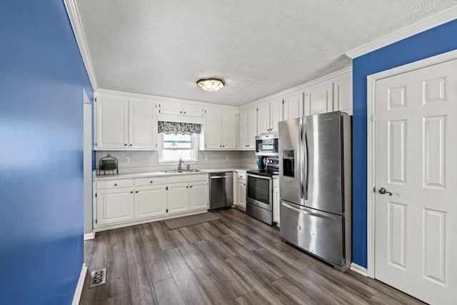 kitchen with white cabinets, sink, ornamental molding, dark hardwood / wood-style flooring, and stainless steel appliances