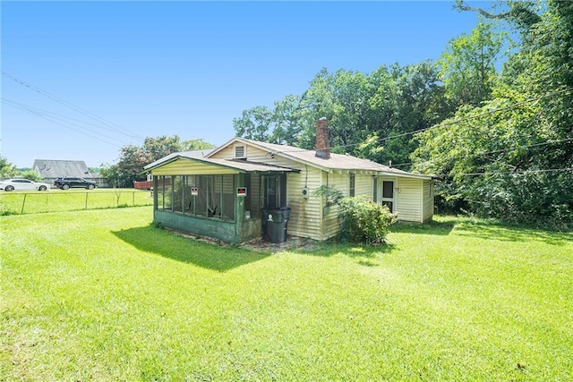 rear view of property featuring a lawn and a sunroom