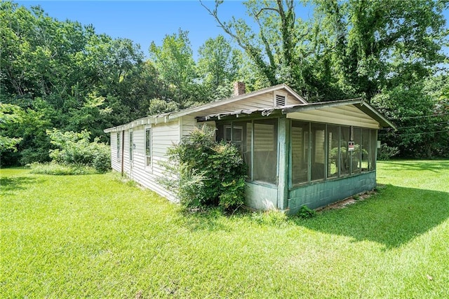 view of home's exterior with a sunroom and a lawn