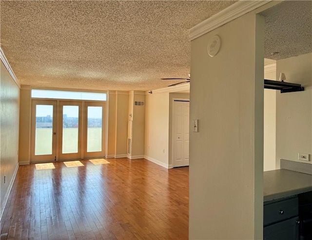 unfurnished living room with hardwood / wood-style floors, french doors, a textured ceiling, and ornamental molding