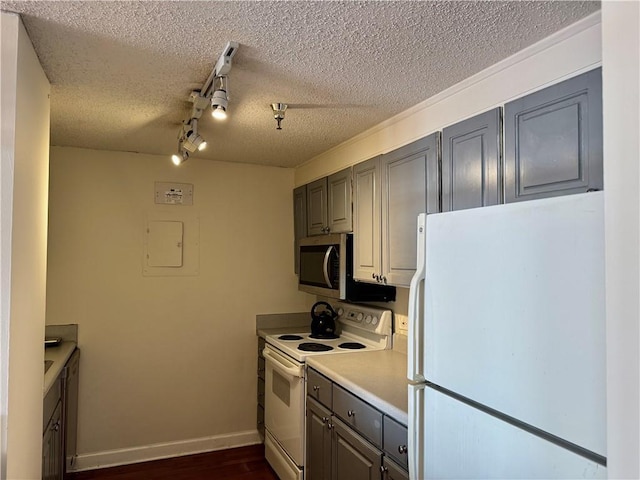 kitchen with gray cabinetry, a textured ceiling, white appliances, light countertops, and baseboards