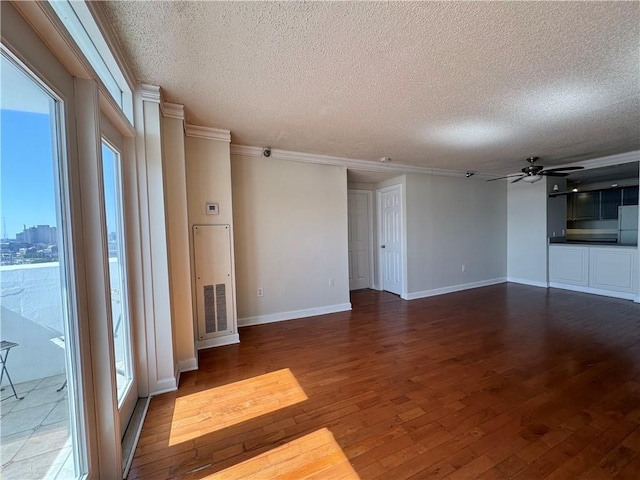 unfurnished living room with a textured ceiling, ceiling fan, dark wood-style flooring, and crown molding