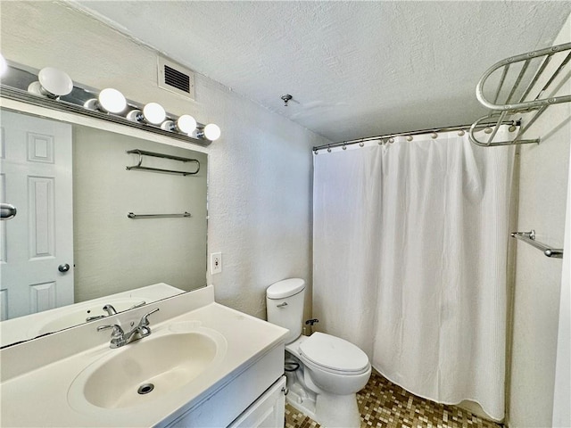 bathroom featuring vanity, visible vents, a textured ceiling, toilet, and a textured wall